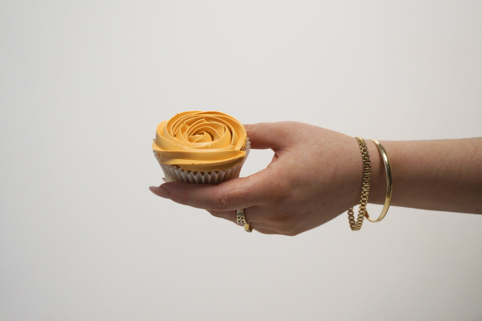 mango coloured cupcake in hand